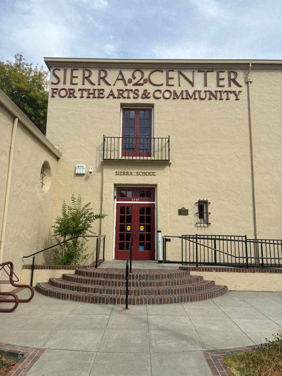 The main entrance of Sierra 2 Center at 2791 24th Street: a cream building with SIERRA 2 CENTER lettering above deep red double doors at the top of curved brick steps.